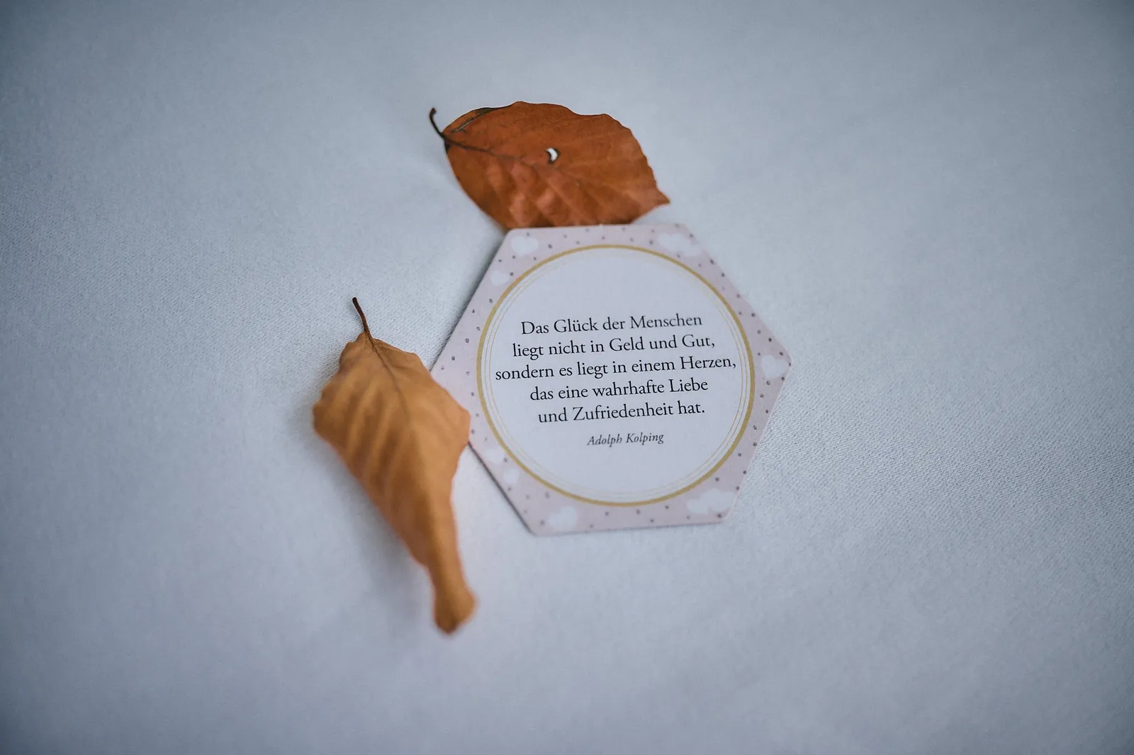Sechseckige Hochzeitskarte mit einem Zitat von Adolph Kolping und zwei Herbstblättern.