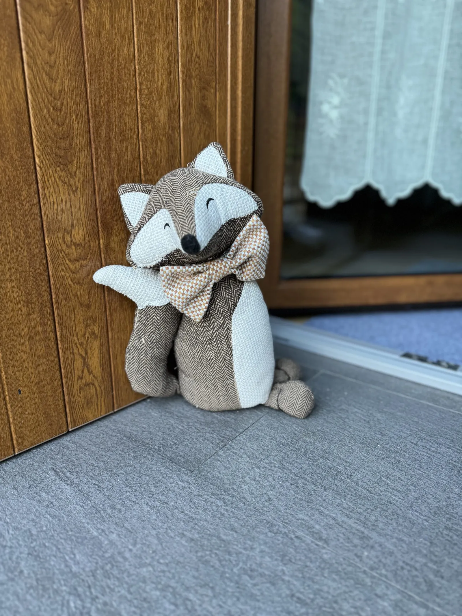 Stoff-Fuchs als Türstopper auf dem Boden vor einer Holztür.