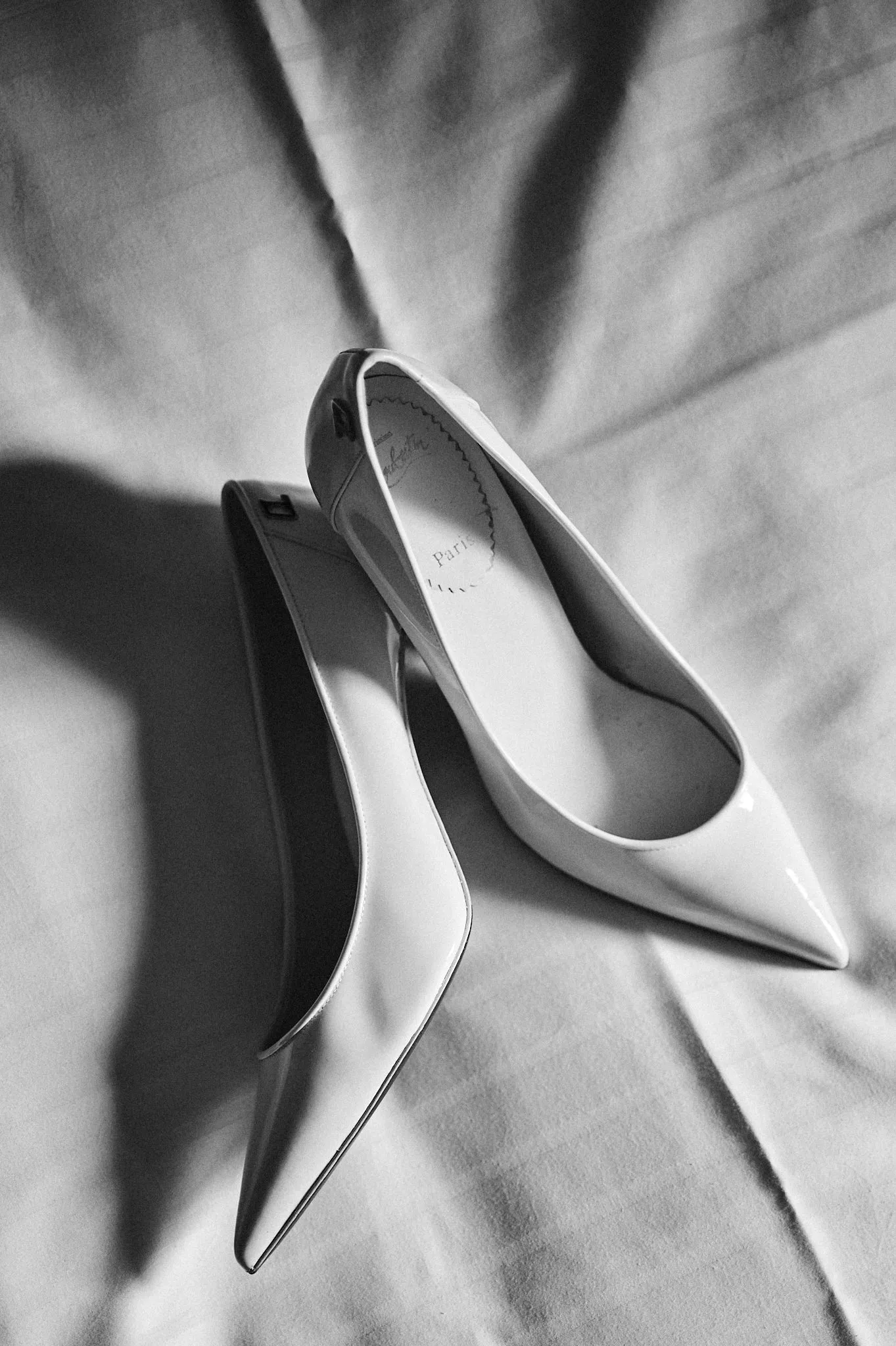Hochzeitsschuhe in weiß von Christian Louboutin liegen auf dem Bett