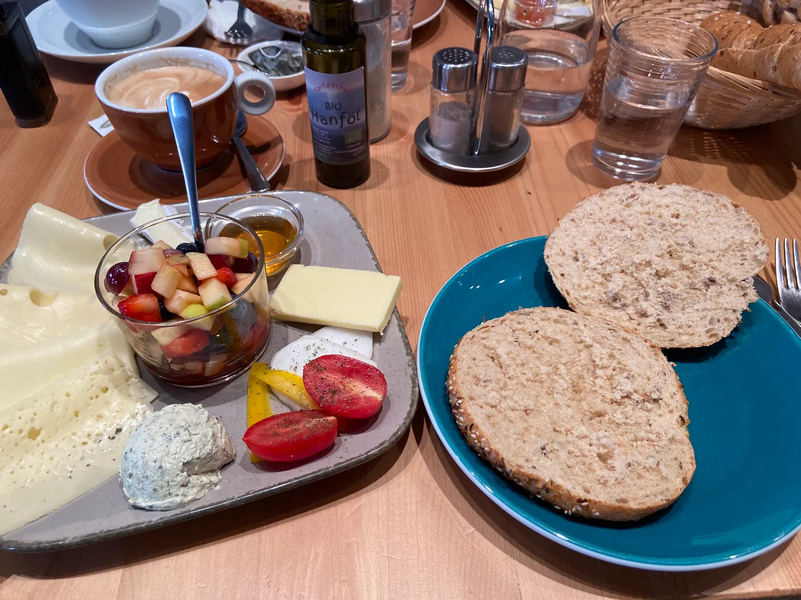 Frühstücksplatte im Seelenfutter mit Käse, Obstsalat, Tomaten und Kräuterfrischkäse, dazu ein Vollkornweckerl.