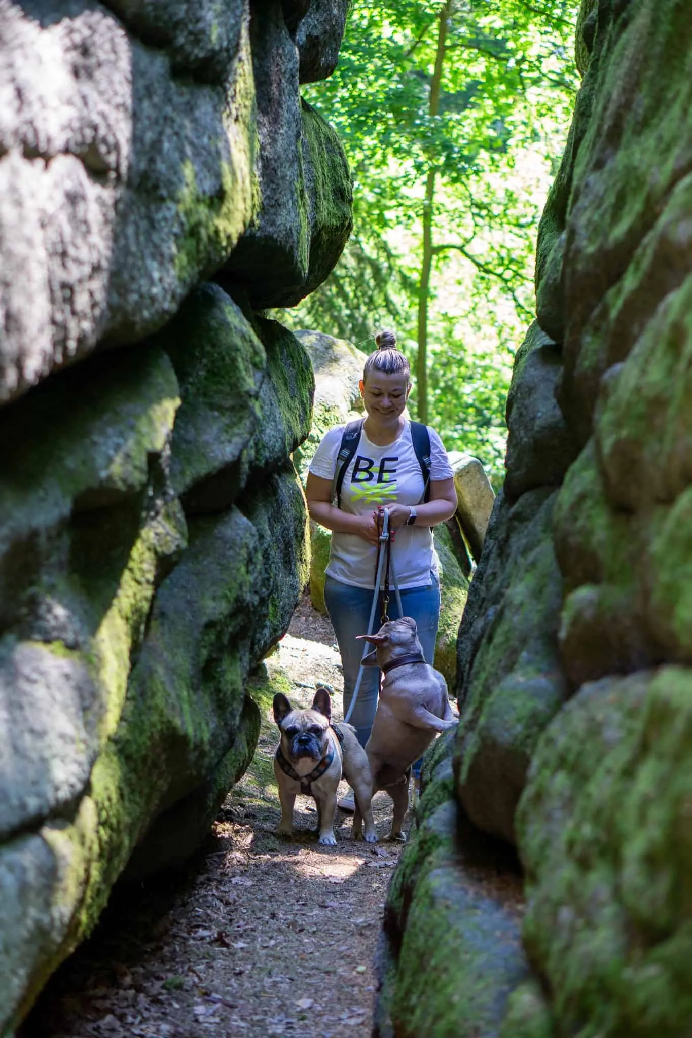 2 Hunde und Frau am Weg durch einen Felsspalt