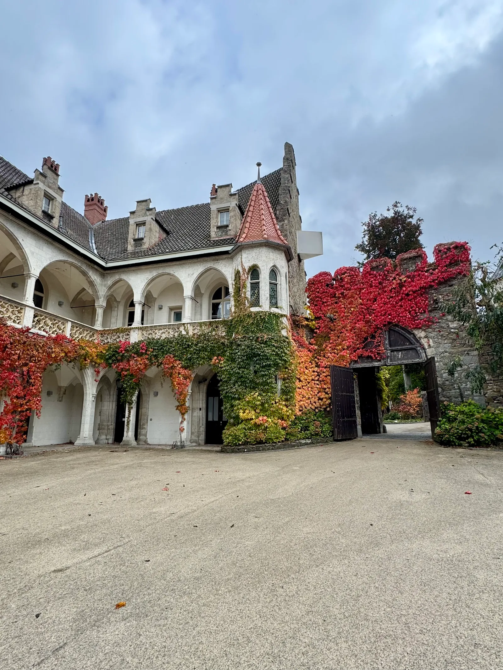 Arkadengang von Schloss Rothschild, dicht bewachsen mit rotem und gelbem Herbstlaub.