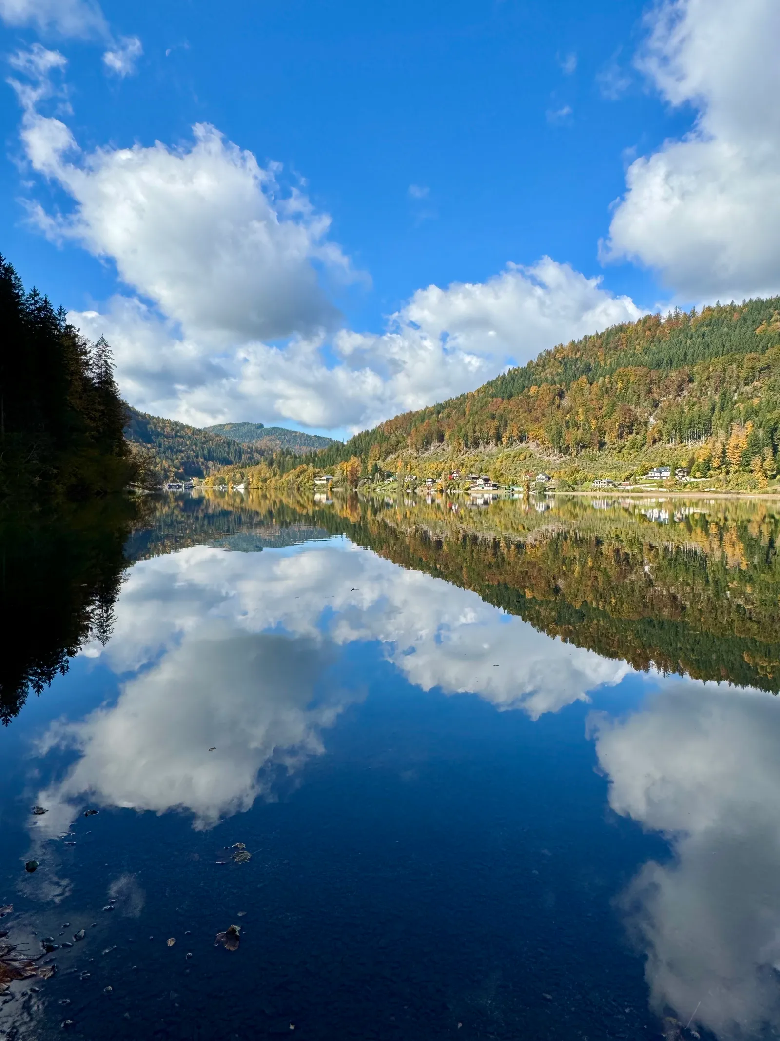 Der Lunzer See spiegelt herbstlich gefärbte Berghänge und Wolken im stillen Wasser wider.