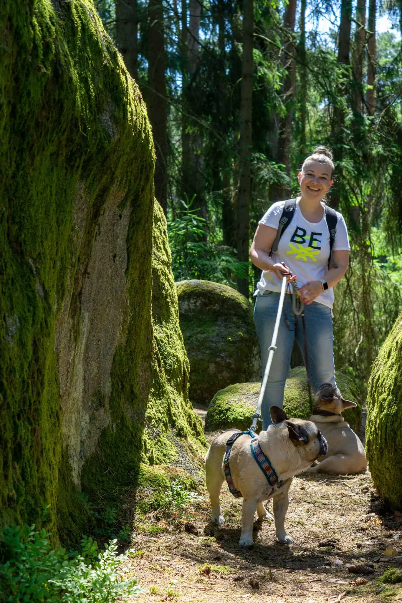 Frau lacht mit 2 Hunden im Wald