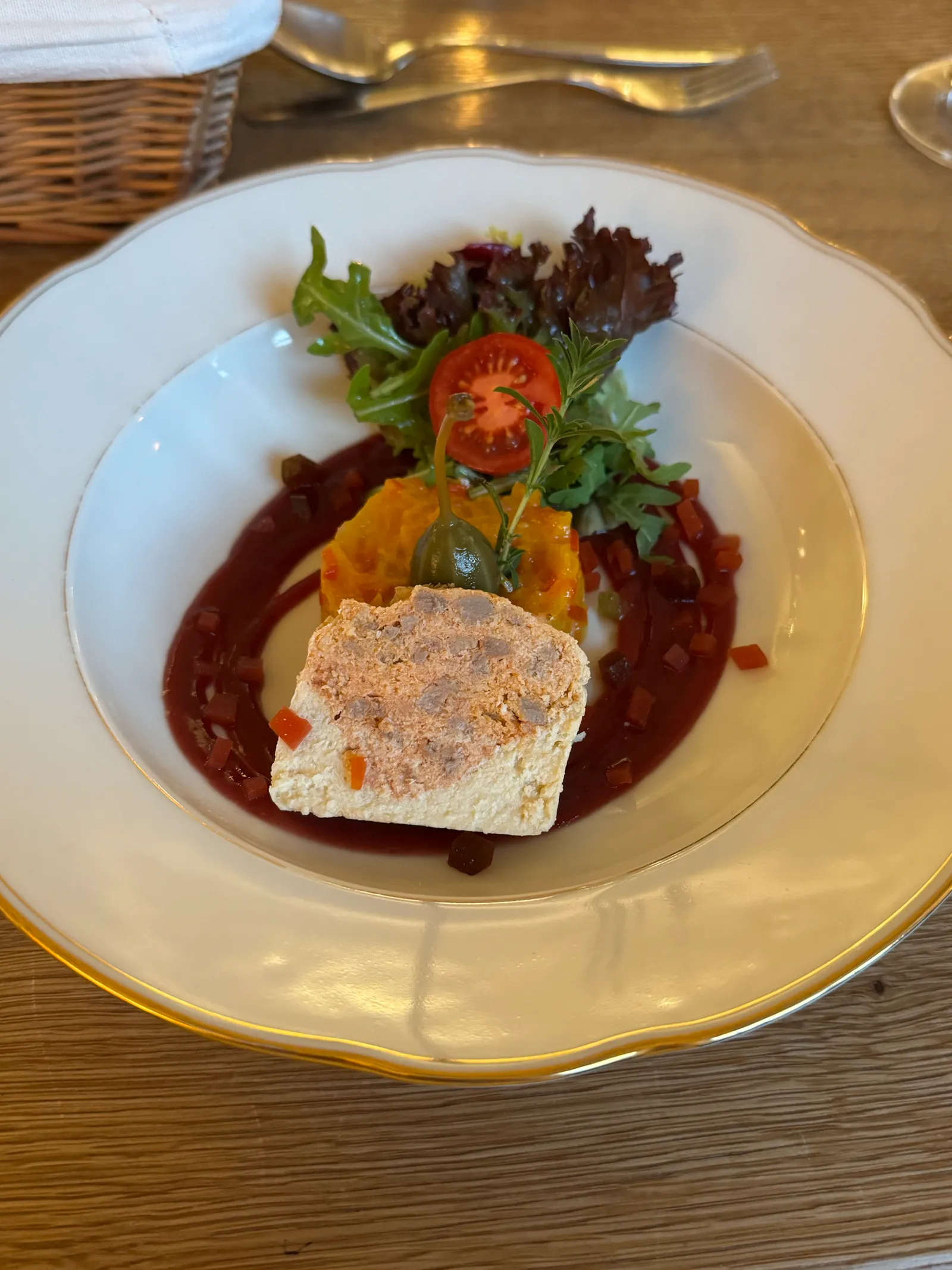 Fleischterrine mit Blattsalat und Paprikasauce auf einem weißen Teller im Hotel Fahrnberger.