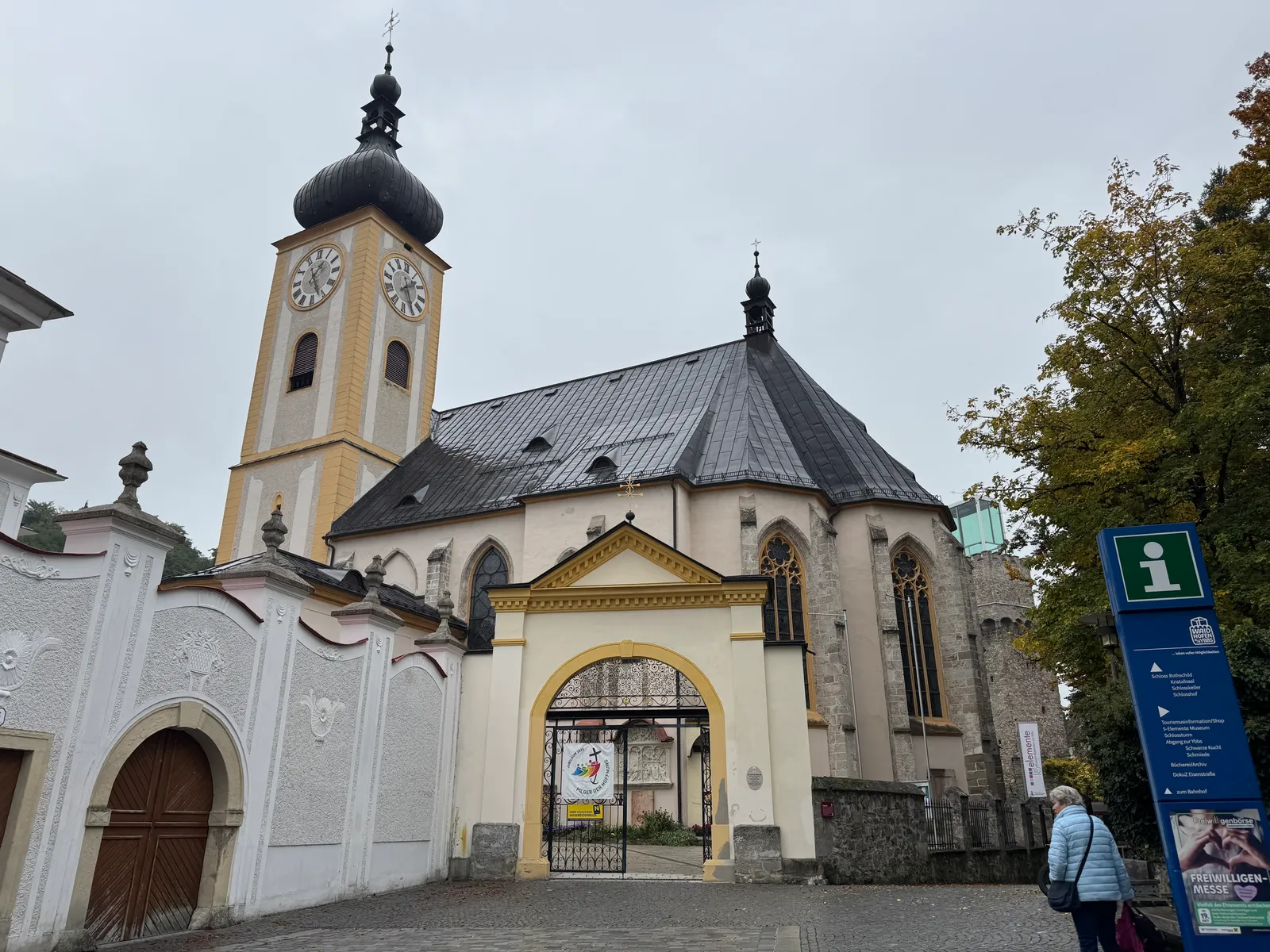 Kirche mit gelbem Turm in Waidhofen an der Ybbs, davor ein schmiedeeisernes Eingangstor.