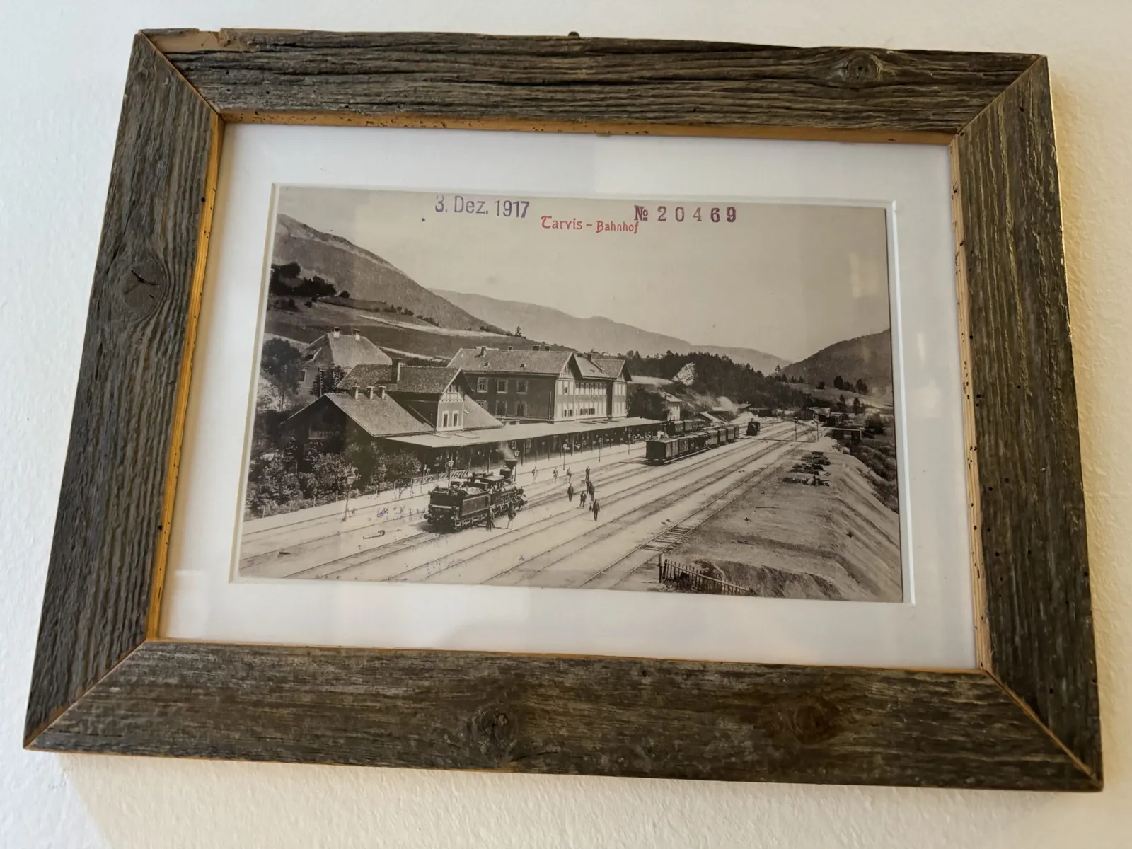 Gerahmte historische Ansichtskarte des Tarvis-Bahnhofs von 1917 mit Zügen am Bahnsteig.