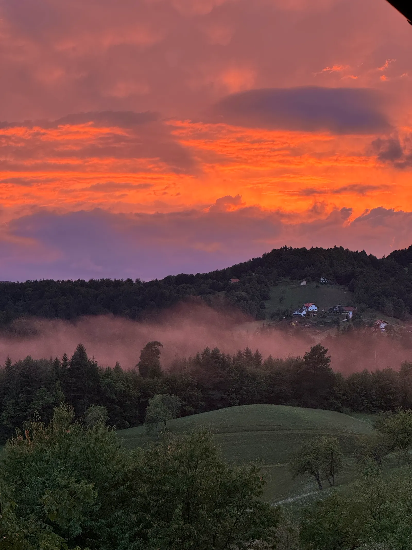 Abendrot über bewaldeten slowenischen Hügeln beim Lavender Hill, Nebel zieht durchs Tal.
