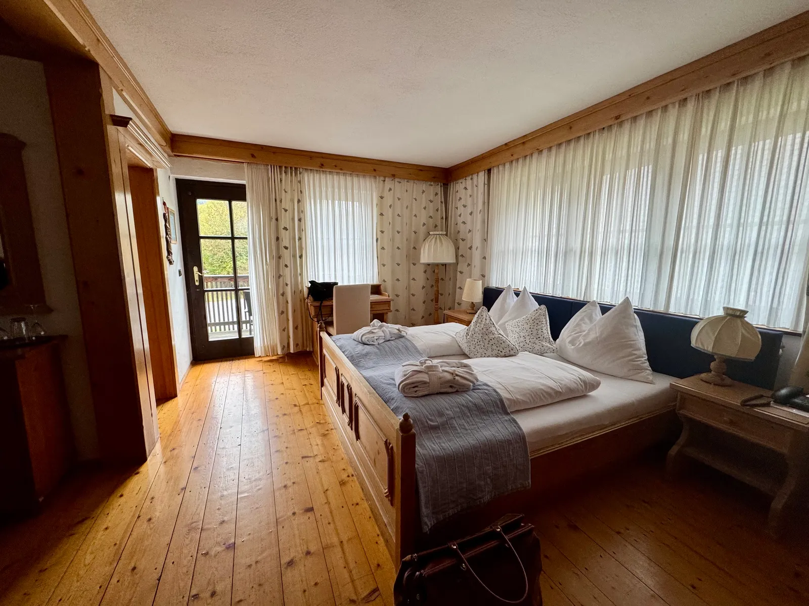 Zimmer im Hotel Fahrnberger mit Holzbett, Dielenböden und Balkonausgang.