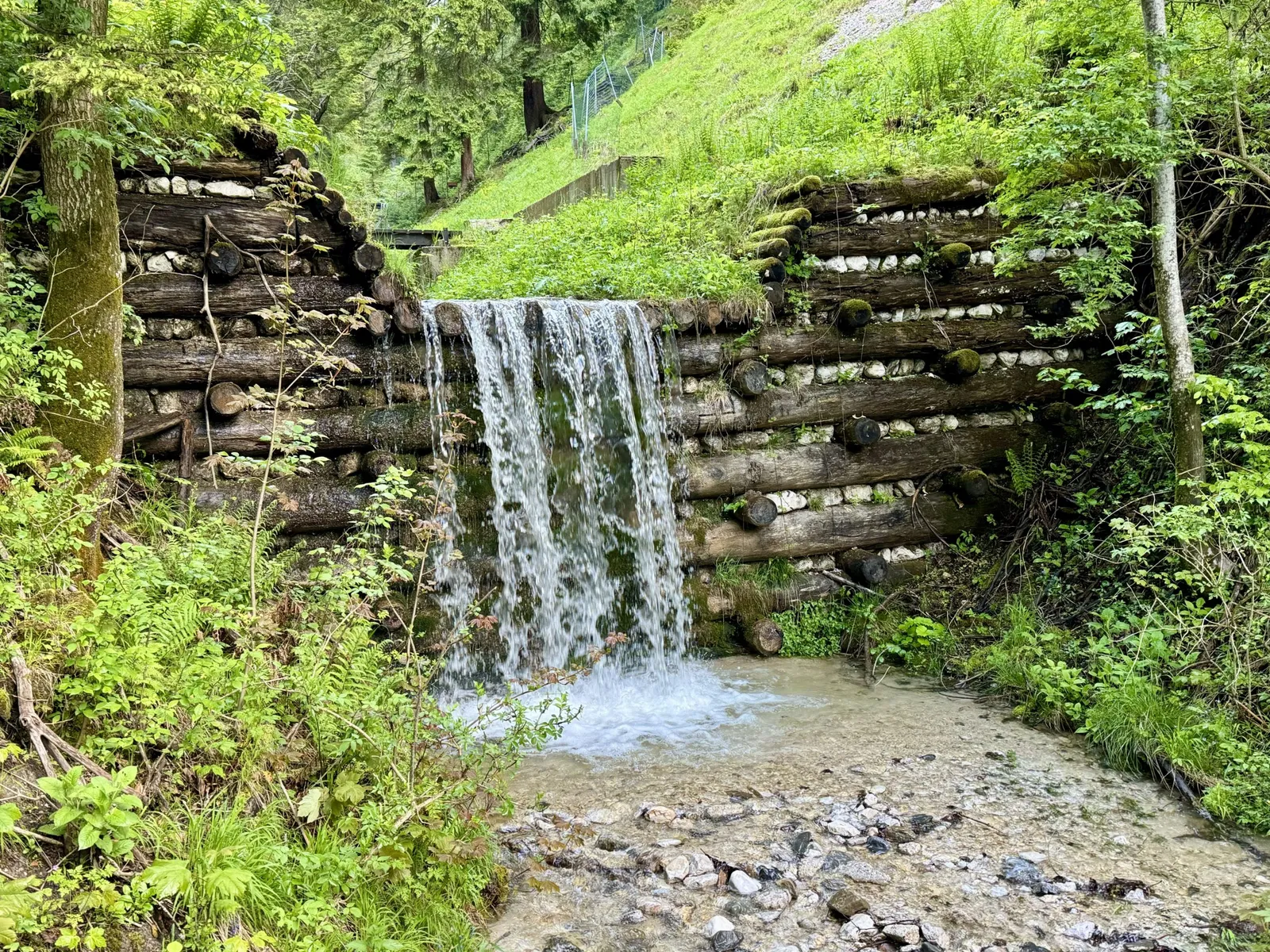 Wasserfall über eine alte Holzbalken-Verbauung am Bärentrail in Tarvisio.