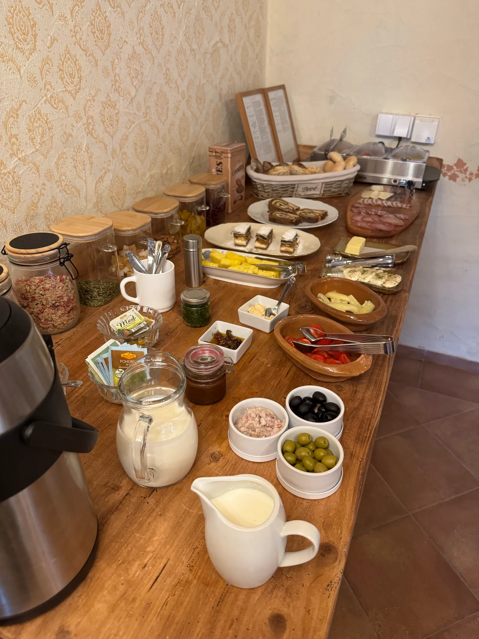 Frühstücksbuffet im Lavender Hill Eco Resort mit Brot, Käse, Oliven, Aufstrichen und Müsli auf einem Holztisch.