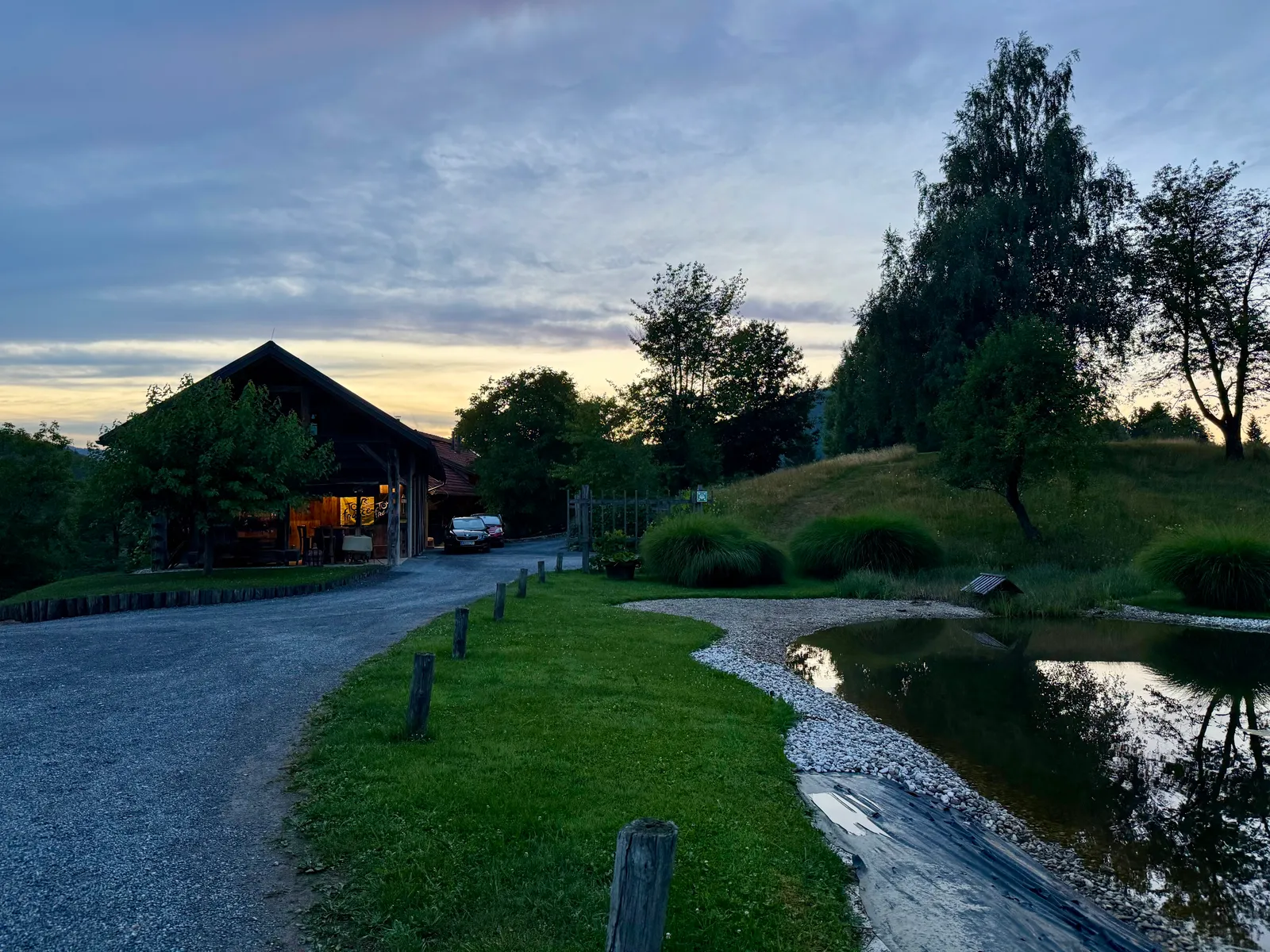 Das Lavender Hill Eco Resort im Abendlicht mit beleuchtetem Gebäude, Teich und buntem Himmel.
