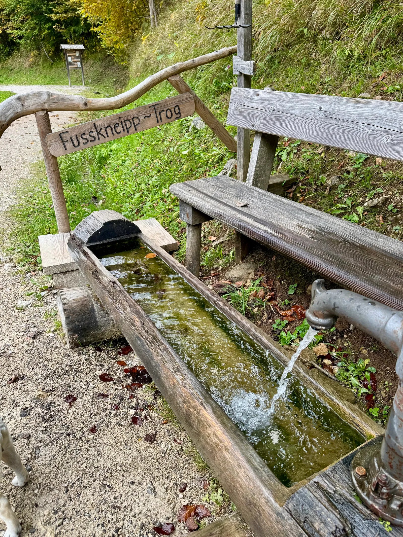 Hölzerner Fusskneipp-Trog mit fließendem Wasser und Sitzbank im Mendlingtal.