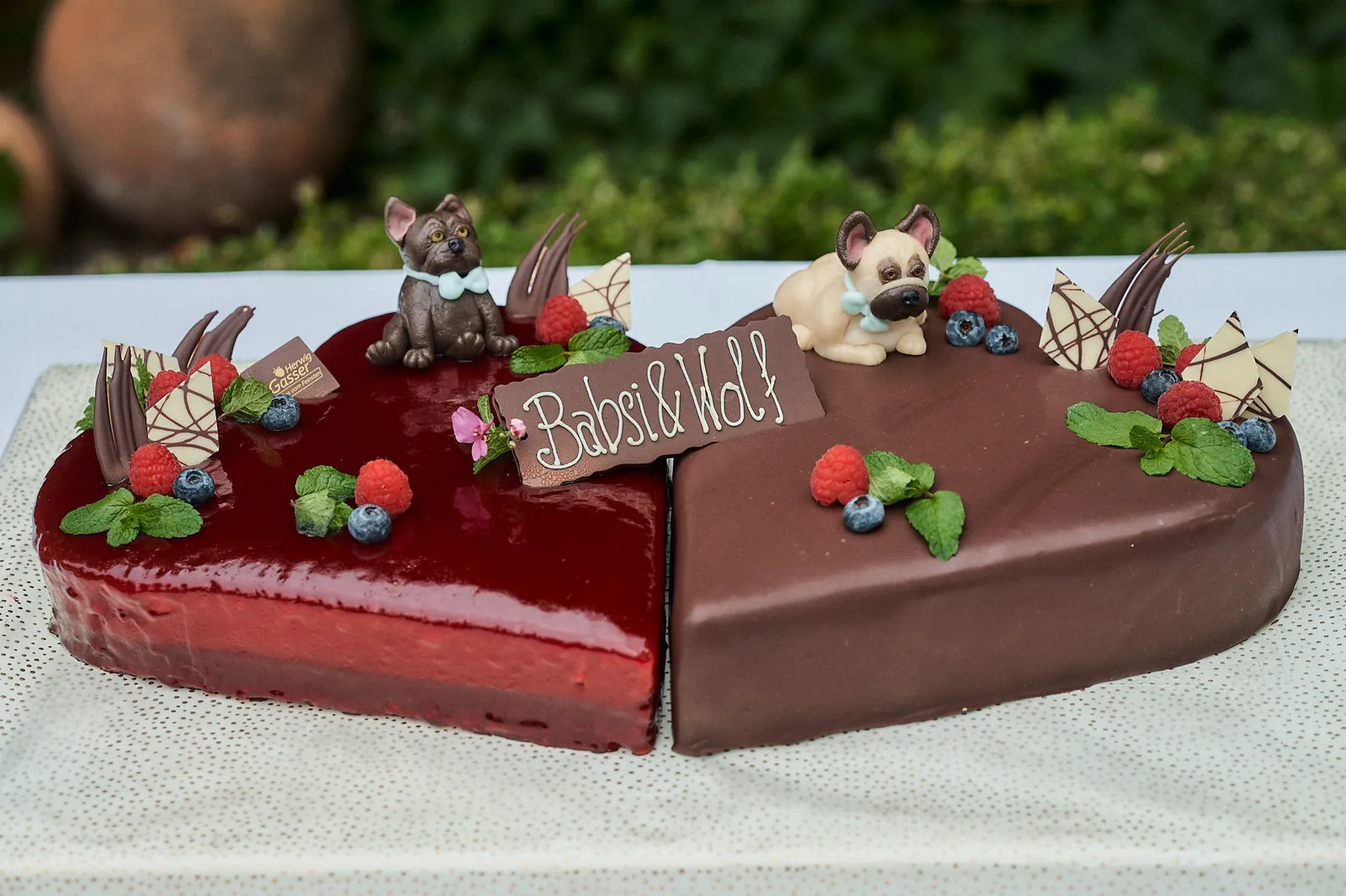 Herzförmige Hochzeitstorte für Babsi & Wolf, eine Hälfte in rotem Beeren-Spiegel, die andere mit Schokoladenglasur.