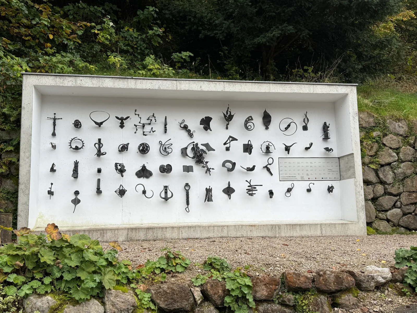 Zahlreiche kleine Schmiedeobjekte auf einem weißen Außenkasten in Ybbsitz ausgestellt.