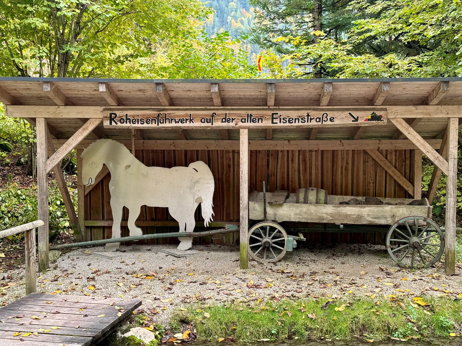 Schauobjekt im Mendlingtal: ein historisches Fuhrwerk mit Pferde-Silhouette unter einem Schutzdach.