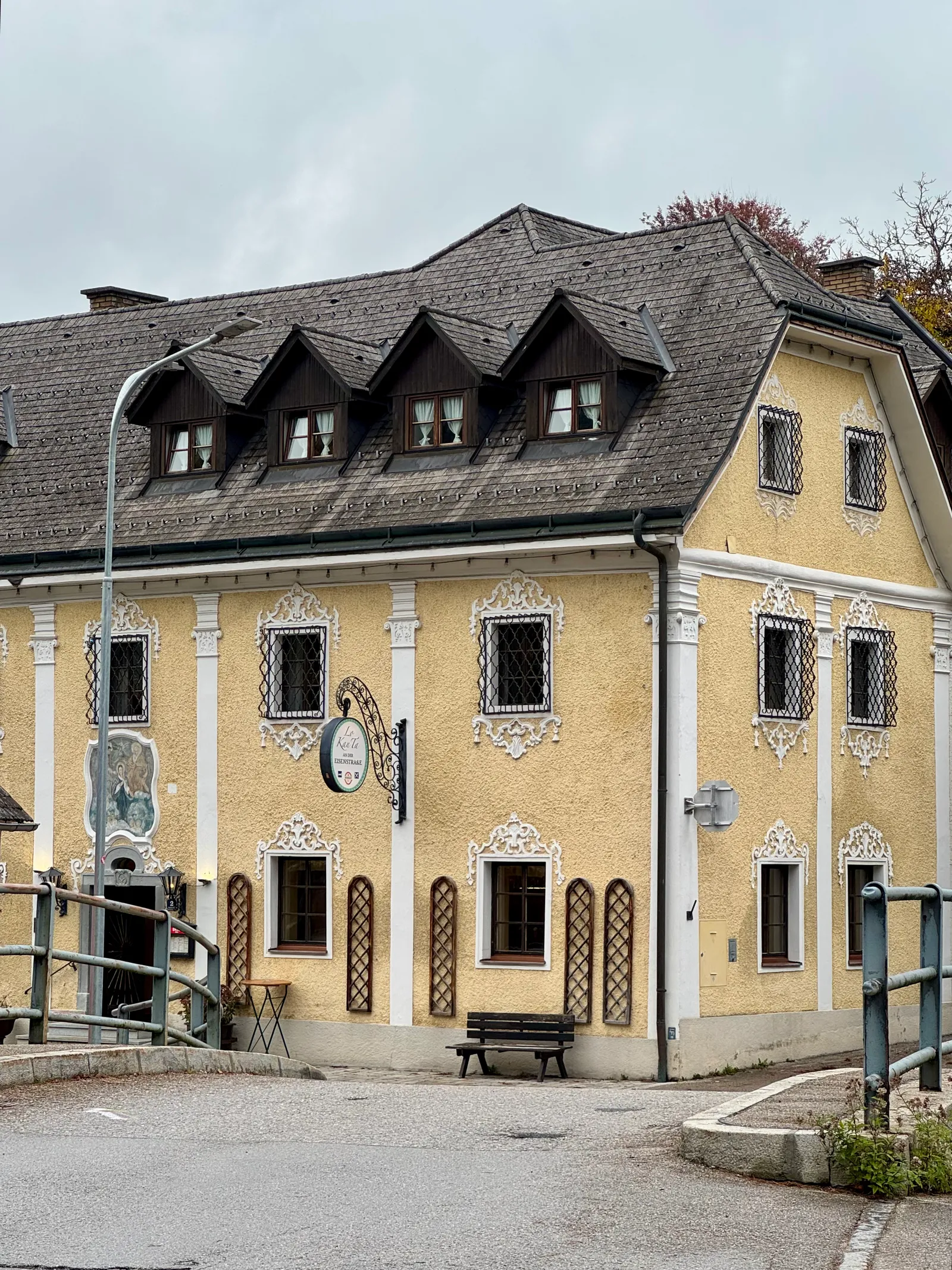 Gelbes Barockgebäude mit weißen Stuckornamenten und Wirtshausschild in Ybbsitz.