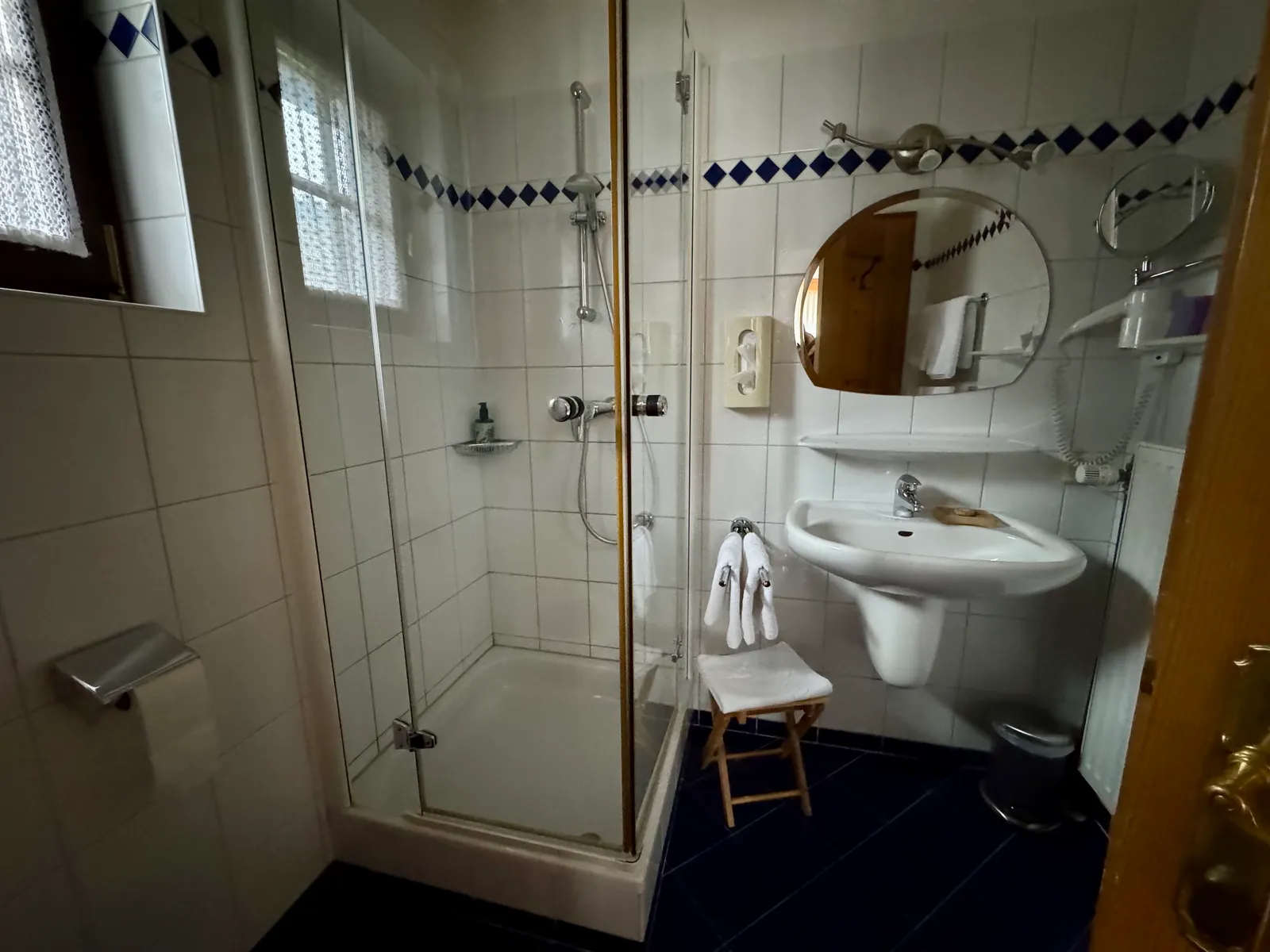 Badezimmer im Hotel Fahrnberger mit Glasdusche und weiß-blauer Fliesung.