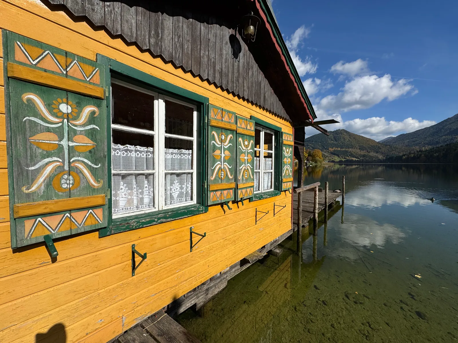 Gelbes Bootshaus mit bemalten grünen Fensterläden steht direkt am Lunzer See.