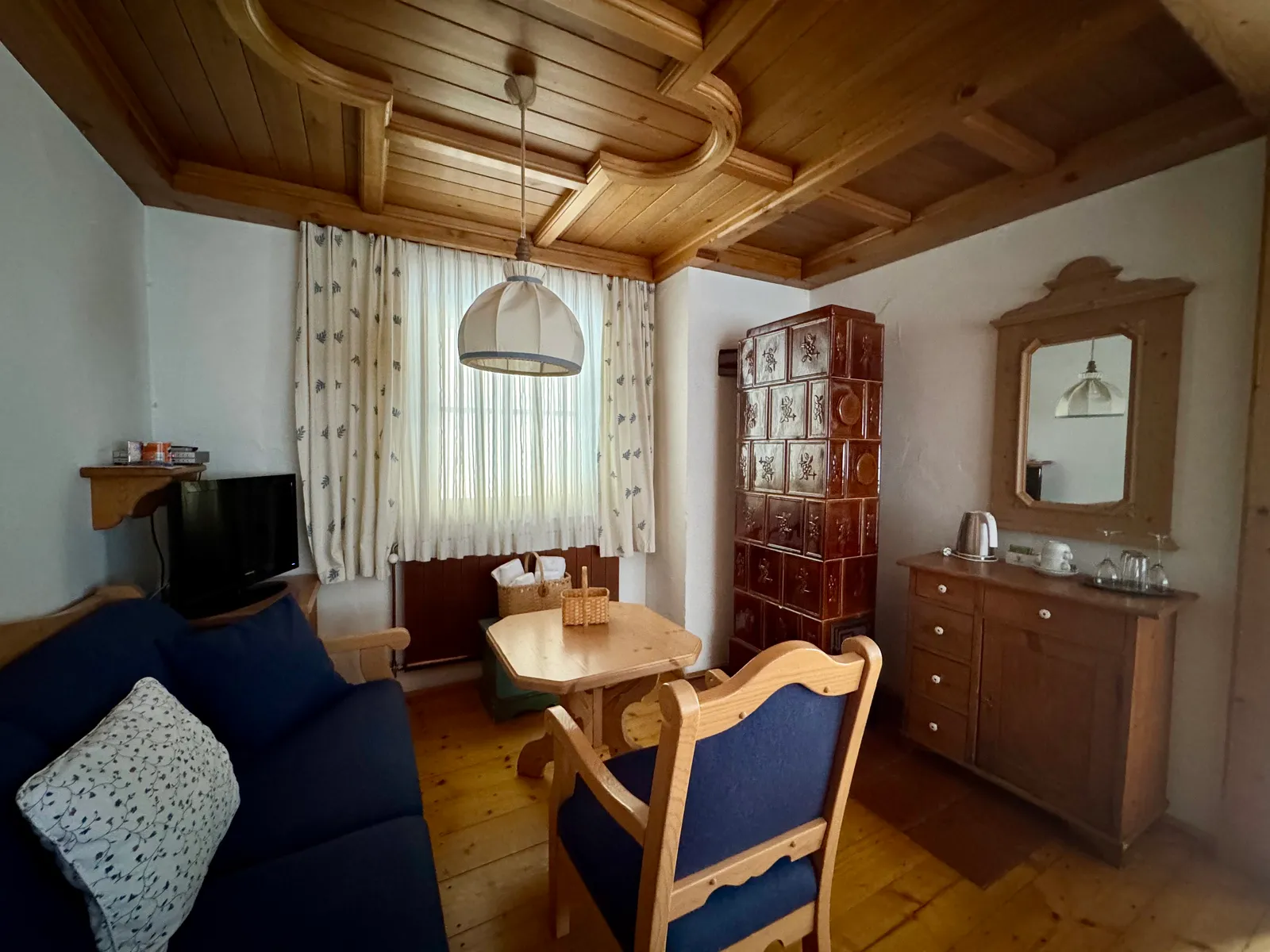 Wohnzimmer im Hotel Fahrnberger mit Kachelofen, Holzdecke und Sitzecke.