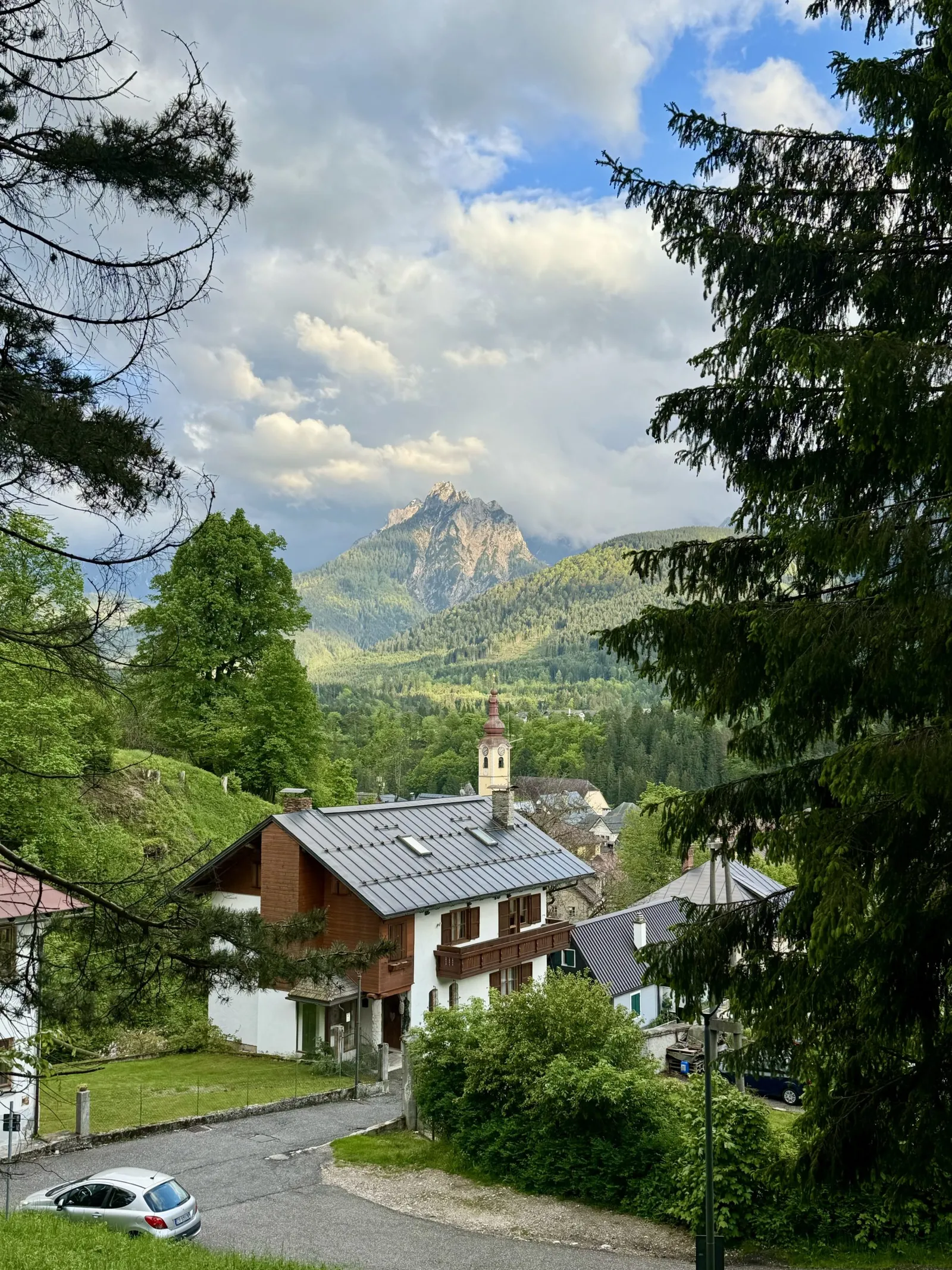 Blick auf Tarvisio mit Kirchturm und einem Berggipfel im Hintergrund.