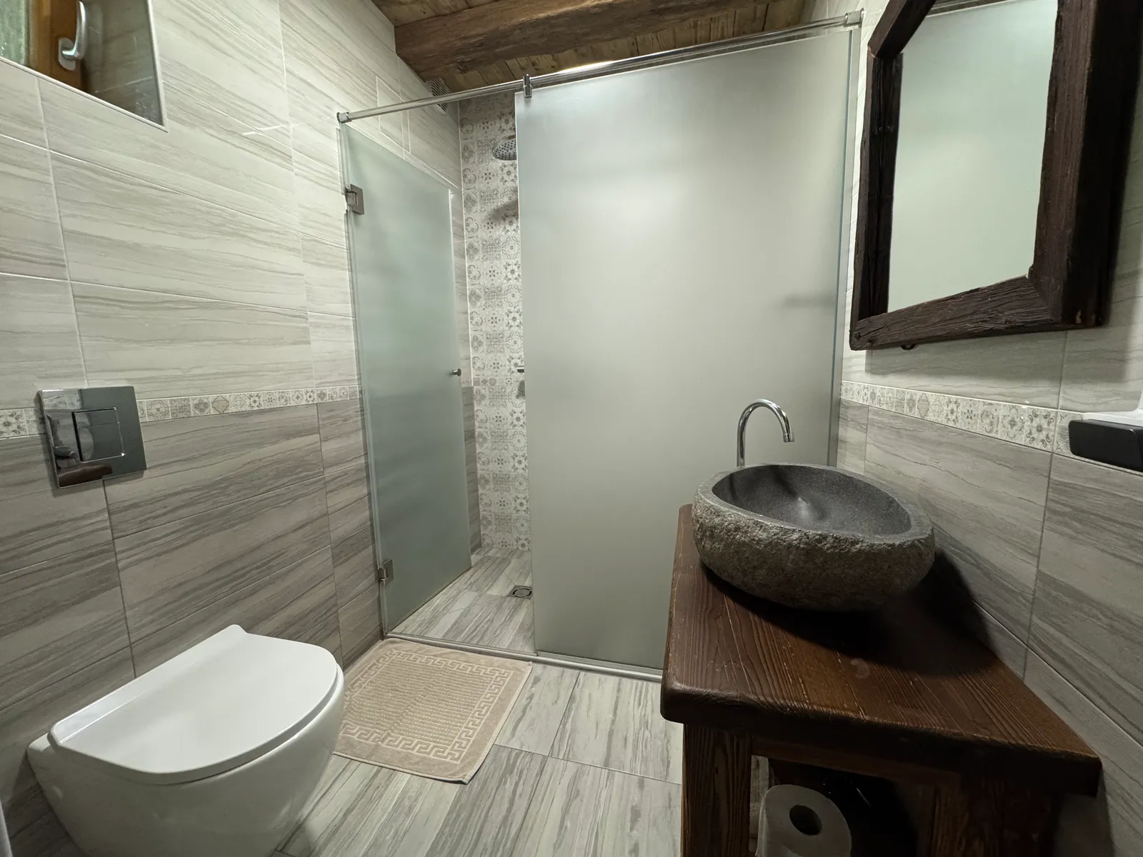 Badezimmer im Lavender Hill Eco Resort mit Glasdusche, Steinwaschbecken auf Holzwaschtisch und WC.