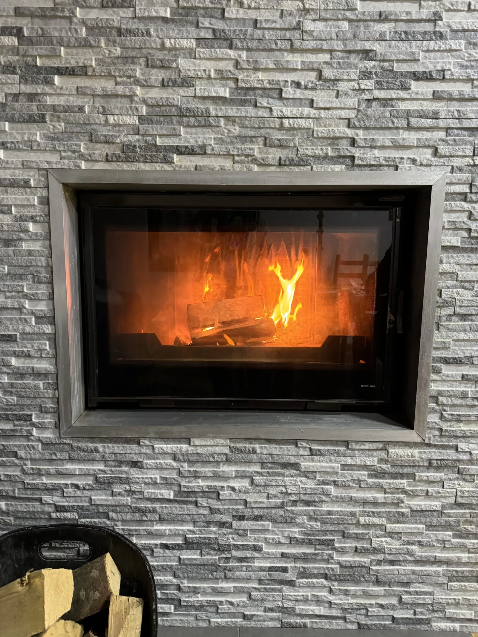 Einbaukamin mit brennendem Feuer in einer Steinverkleidung.