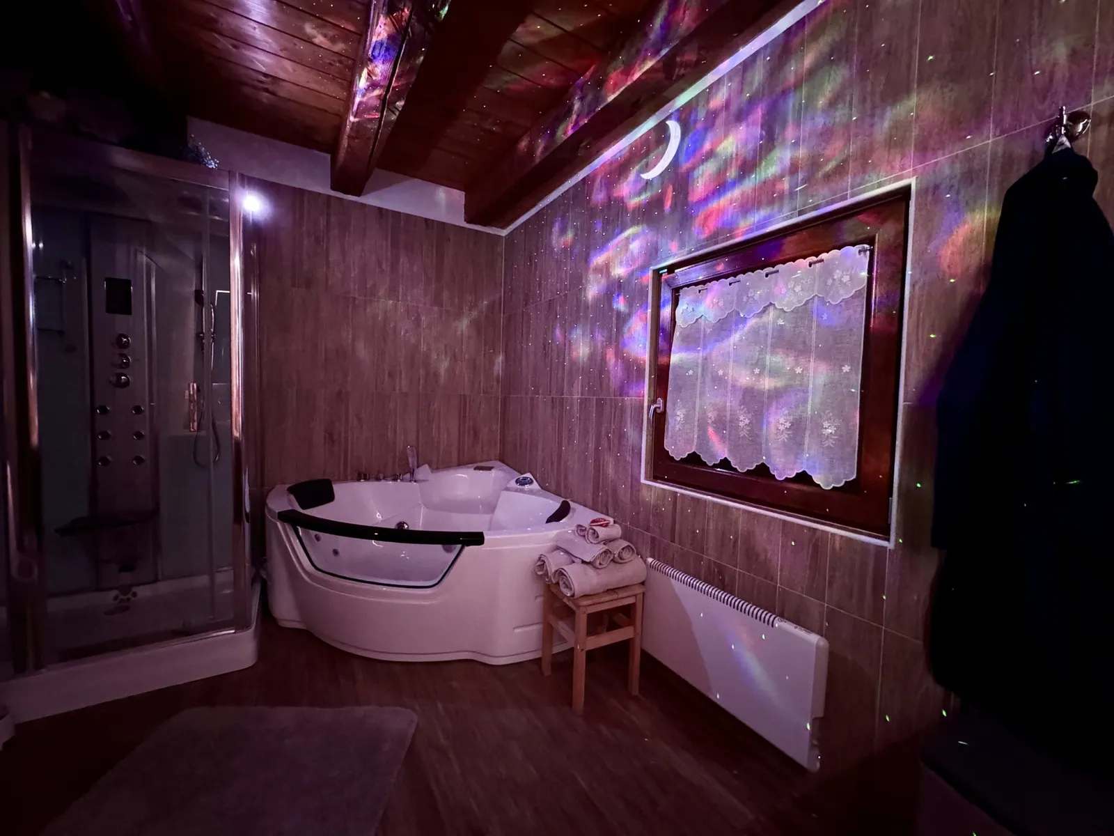Badezimmer mit Whirlwanne und Dampfdusche, bunte Lichtprojektion an Decke und Wänden.