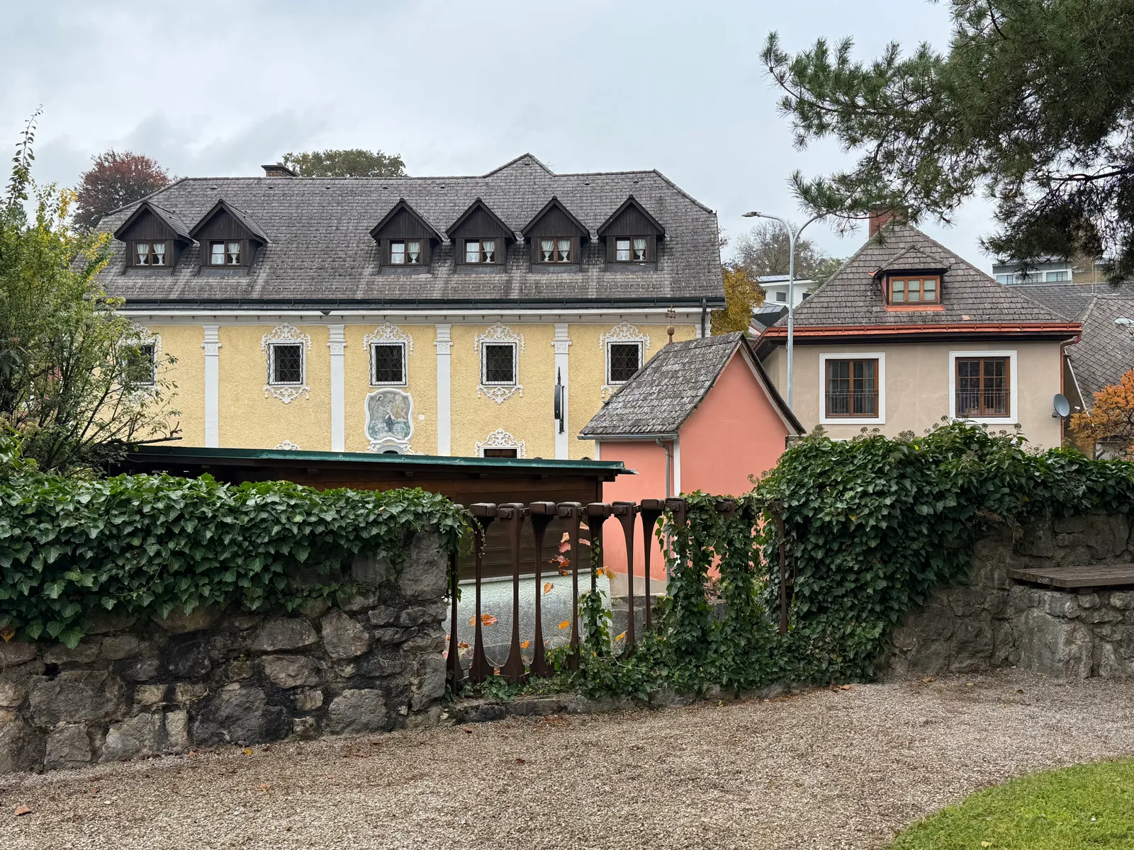 Historische Häuserzeile in Ybbsitz mit gelbem Barockhaus und efeubedeckter Steinmauer im Vordergrund.