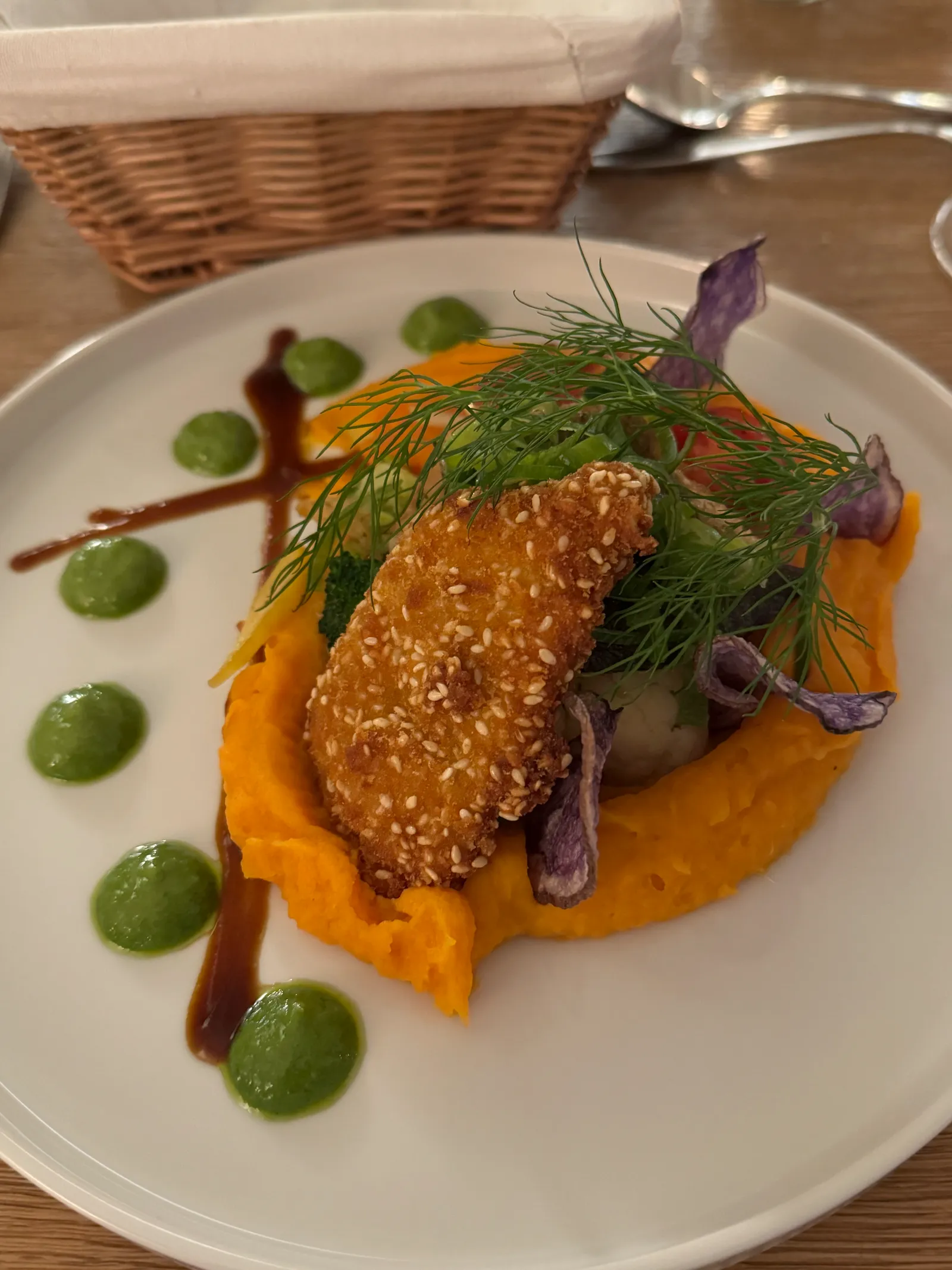 Paniertes Filet auf Süßkartoffelpüree mit grüner Kräutersauce und buntem Gemüse.