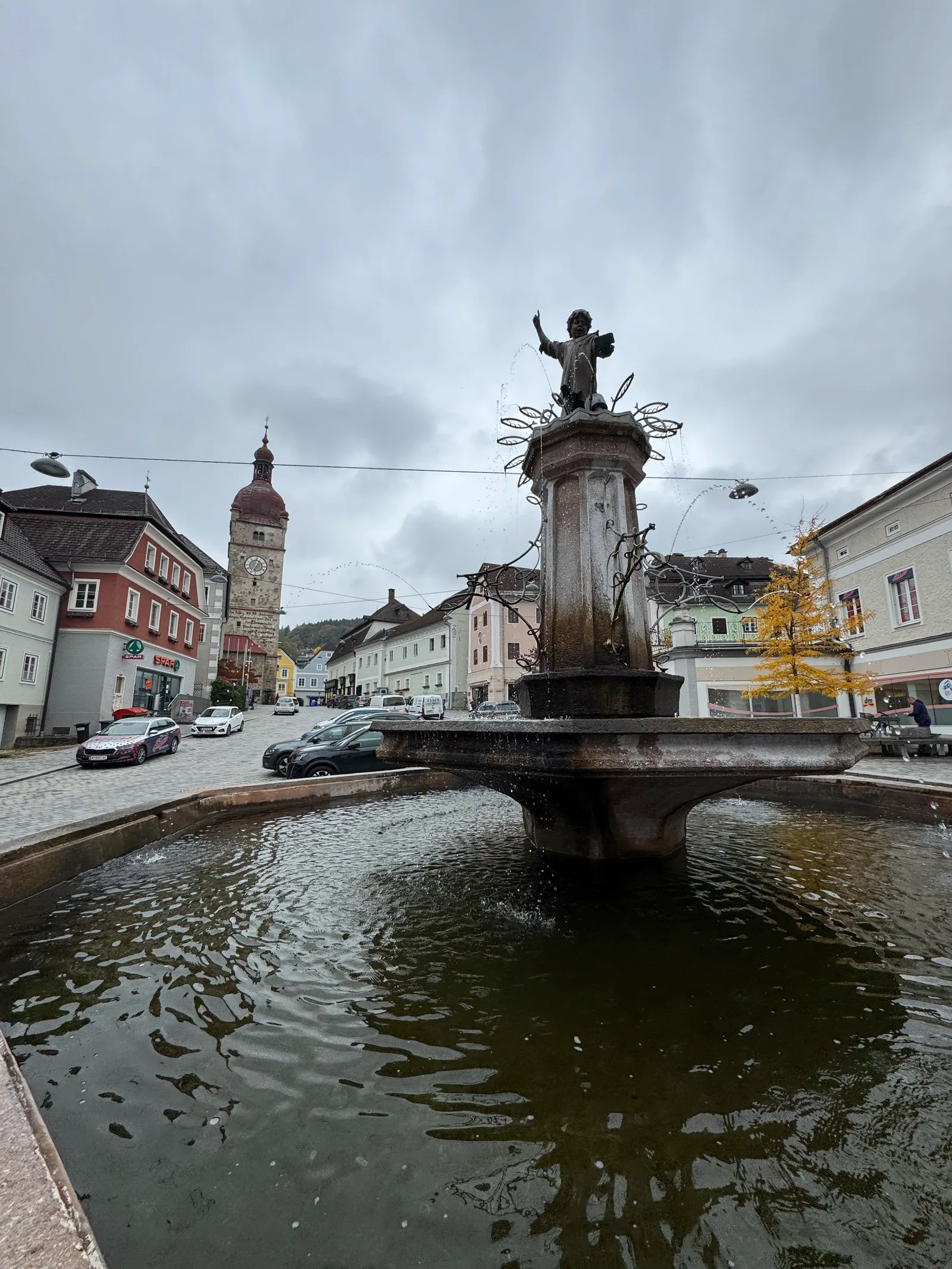 Brunnen mit Figurenskulptur auf dem Stadtplatz in Waidhofen an der Ybbs, Stadtturm im Hintergrund.